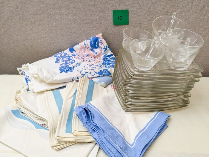 10. (3) Vintage Tablecloths/Napkins, (12) Square Glass Plates + (6) Mugs